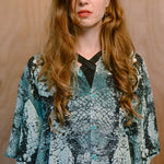 Woman wearing a Green Ophidian bamboo shirt against a wooden wall