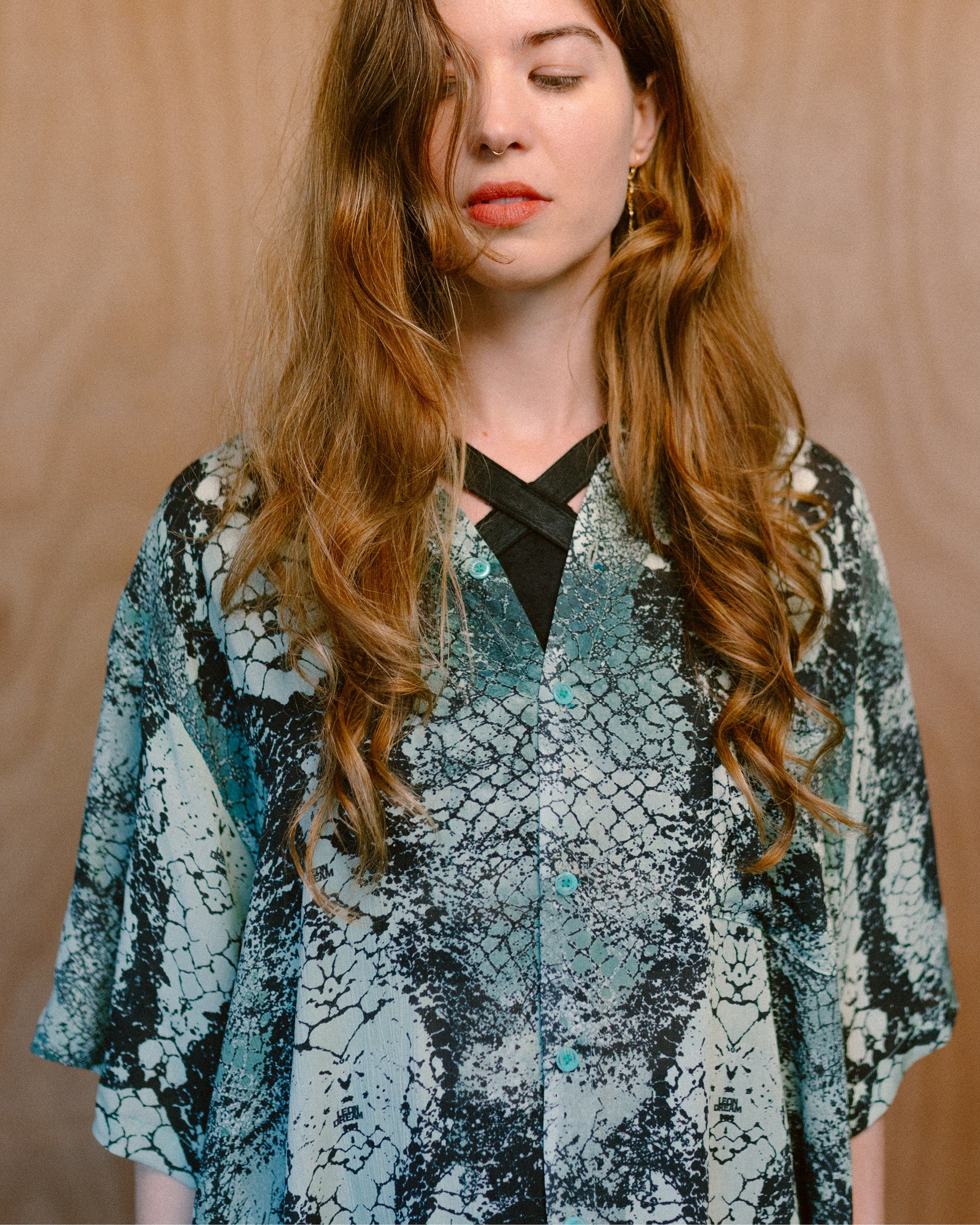 Woman wearing a Green Ophidian bamboo shirt against a wooden wall